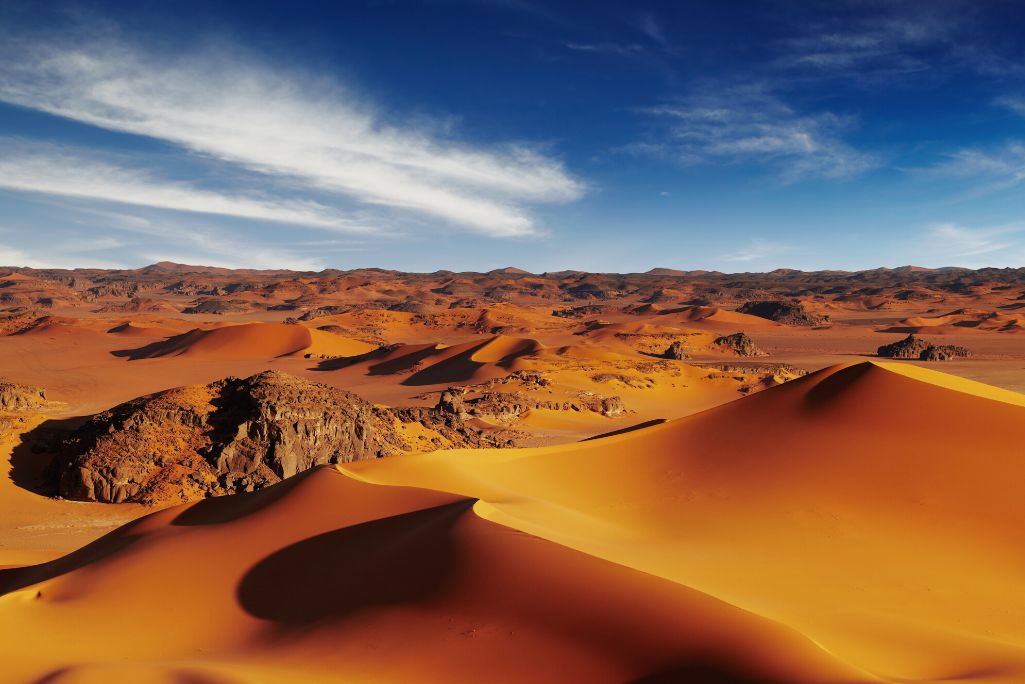 Sand dunes and rocky outcrops under a deep blue desert sky, Sahara
