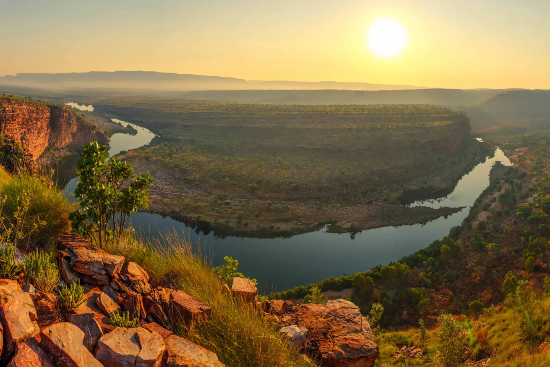 A river bending around a sandstone plateau in the Kimberley, Australia, in low golden light
