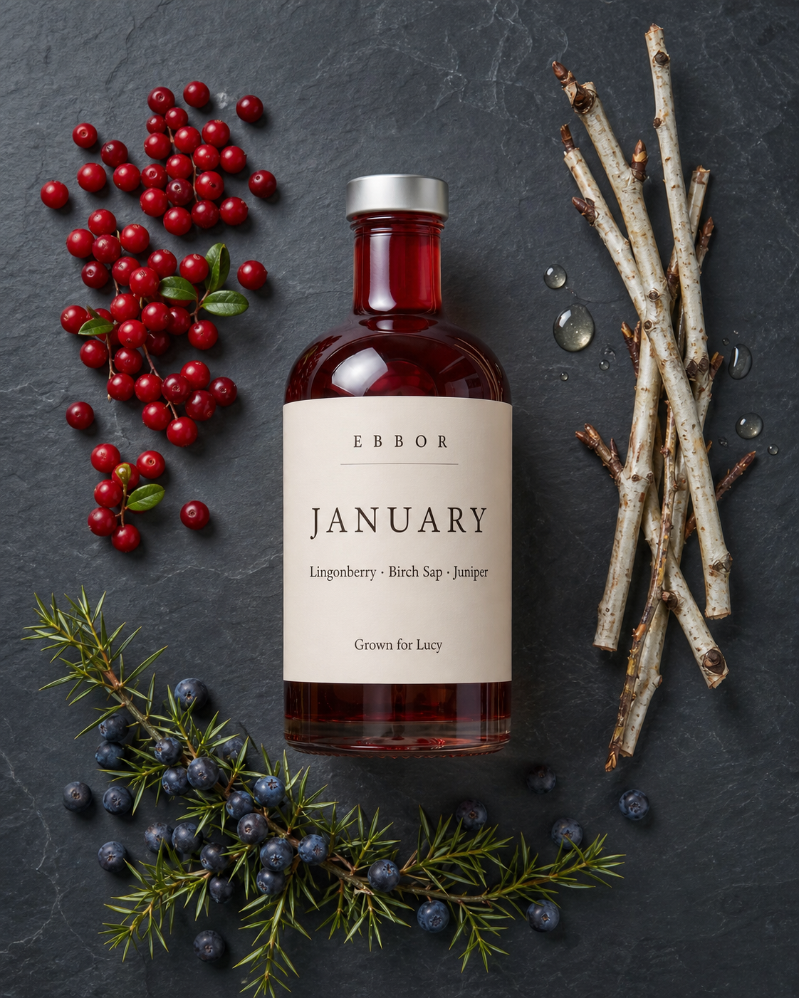 A January edition bottle of lingonberry, birch sap and juniper, personalised for Lucy, laid flat beside its plants