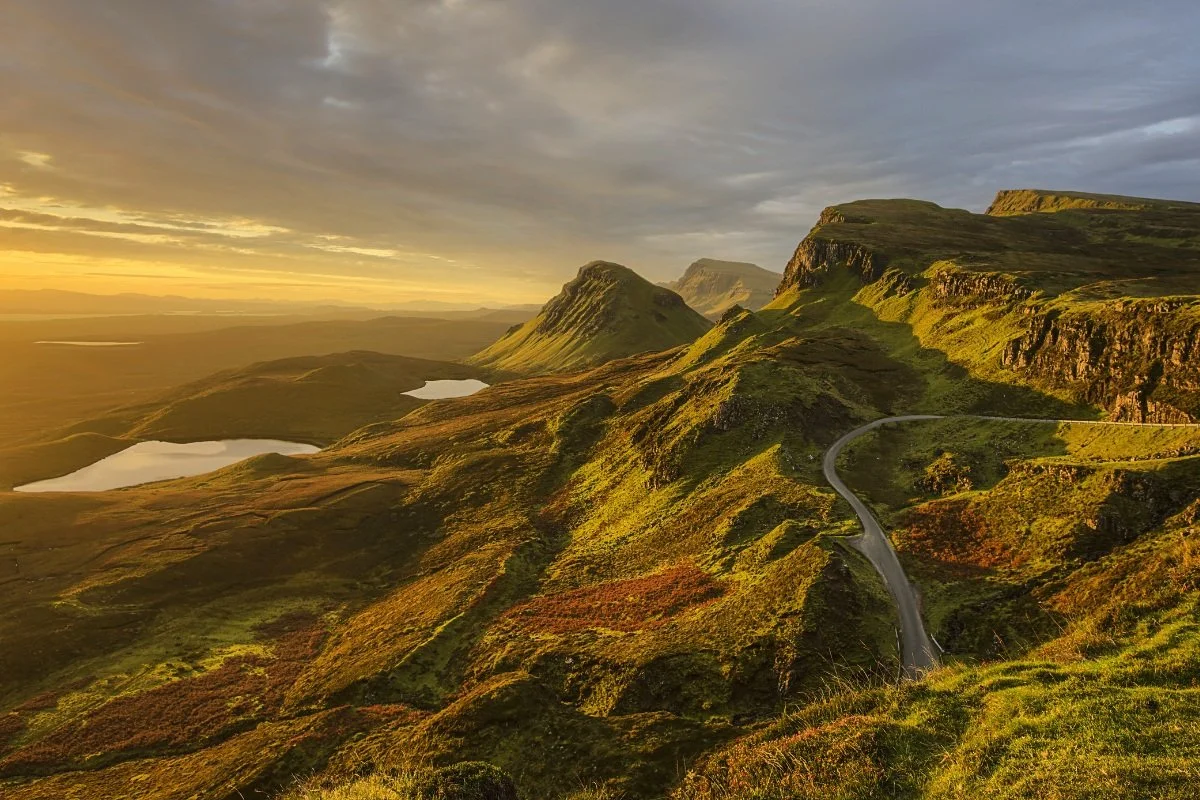 Green ridges and small lochs in golden morning light in the Scottish Highlands