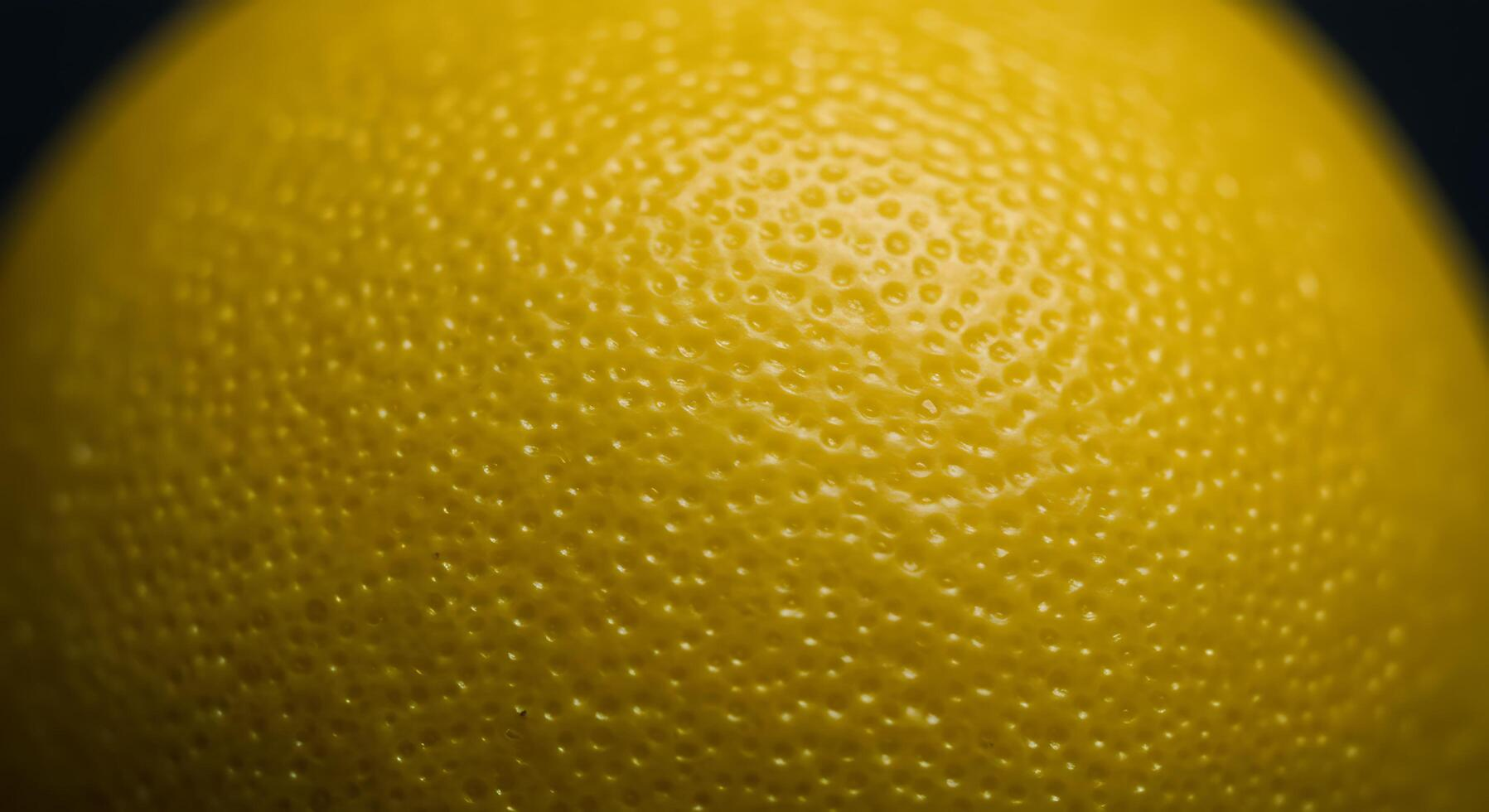 A macro photograph of yellow citrus peel, tightly cropped