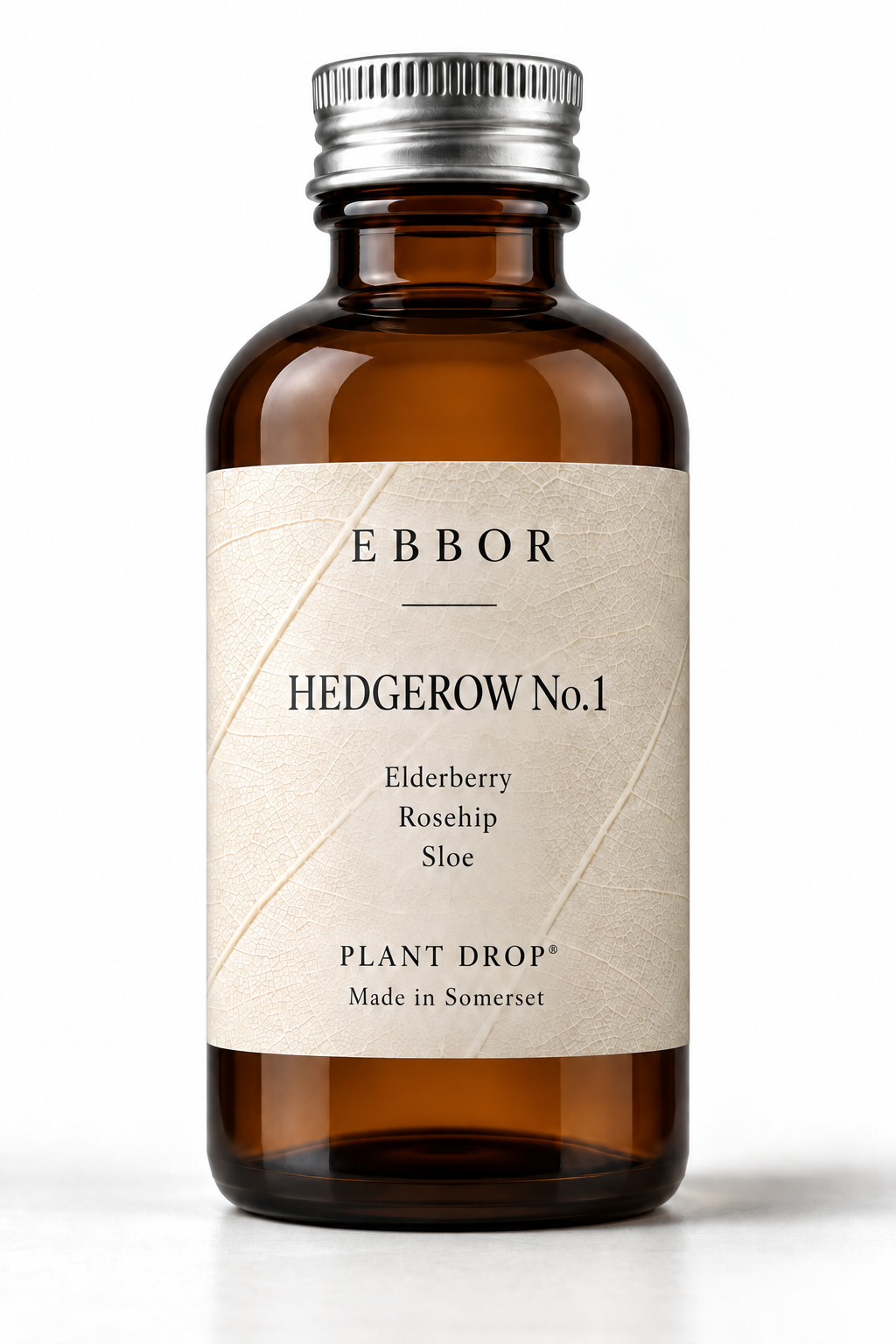 An amber glass Hedgerow No.1 Plant Drop® bottle with a knurled silver cap, standing on a seamless white ground with a soft shadow; its label reads Hedgerow No.1, Elderberry, Rosehip, Sloe, Made in Somerset